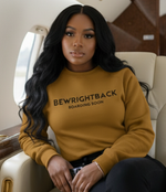 Woman sitting in a luxurious airplane cabin wearing a mustard yellow sweater with text.